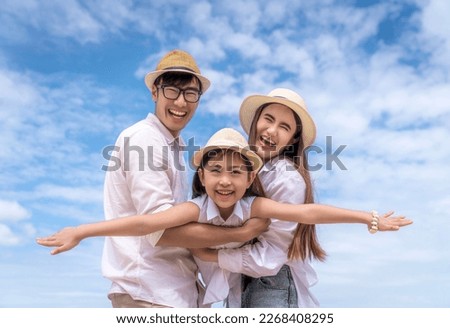 Asian family father, mother and daughter playing togather in fly action with beach and summer background in holiday time