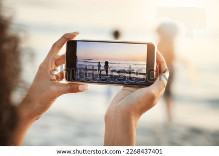 Phone, photograph and beach with a woman in nature, recording her playing kids by the ocean outdoor. Mobile, family and sunset with a parent taking a picture of her kids on the sand at the sea