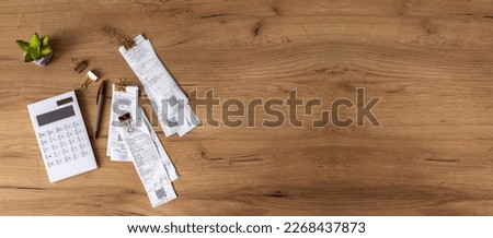 Top view of bills, calculator, pen and decorative plant on wooden able. Free space. Concept of calculating costs and planning payments Royalty-Free Stock Photo #2268437873