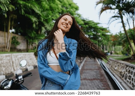 Portrait of a woman brunette smile with teeth walking outside against a backdrop of palm trees in the tropics, summer vacations and outdoor recreation, the carefree lifestyle of a freelance student.