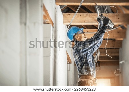 Professional Caucasian Electrician Working on Electrical Wiring System Installation in New Residential House Ceiling. Royalty-Free Stock Photo #2268453223