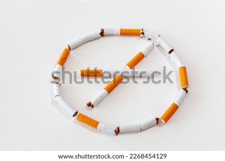 A broken cigarette on a white background. Broken cigarettes in the form of a prohibition sign. Stop smoking
