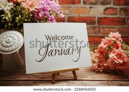 Welcome January  text with flower bouquet decoration on wooden and old brick wall background