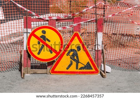 Signs "Road works" and fencing next to the dug-up road. Repair of communications. Road sign pedestrian traffic is prohibited. Repair of the road surface.