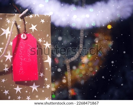 Merry Christmas gift tag greeting on festive background with snow effect overlaymedium shot shot selective focus