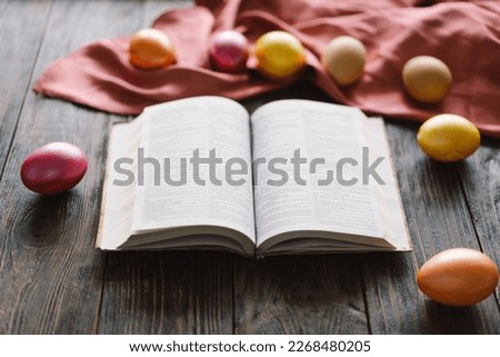 Traditional holiday symbol. Multicolored Easter eggs and holy bible on a wooden background. Religion concepts