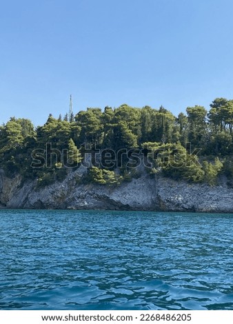 Small rocks covered with green trees in the blue sea. Photo from the water