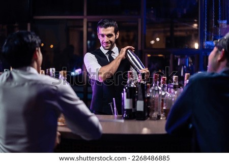 Caucasian profession bartender making a cocktail for women at a bar. Attractive barman pouring mixes liquor ingredients cocktail drink from cocktail shaker into the glass at night club restaurant. Royalty-Free Stock Photo #2268486885