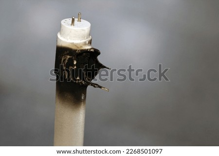 Substandard materials of ledtube a led tube light neon lamp, a burnt led lamp tube due to bad materials, substandard materials concept, hazards of light lamps, fire and industrial security concept Royalty-Free Stock Photo #2268501097