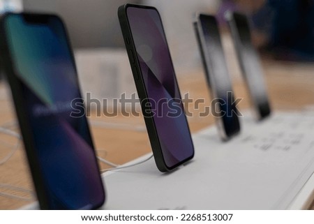 Row of brand new smartphones for sale at electronics store. Department of mobile phones in the tech store. A modern gadget store. Modern tech, communication, network connection, mobility concept.