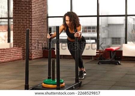 African American athlete is engaged in the gym. A strong woman trains on a crossfit sled. Sport and fitness motivation. Individual sports recreation.