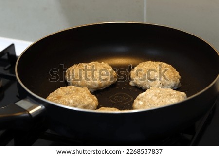 Meat burgers or cutlet-shaped patty being shallow fried in oil on a frying pan, close up. Russian or Polish version of cutlets - kotlety.