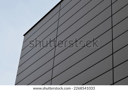 cladding of a building with a expanded metal lattice structure. galvanized gray nets protect the industrial building. Blue sky in contrast to a silver background, wall, corner, slanted, sheet metal