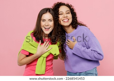 Young two friends cheerful joyful happy fun cool women 20s wearing green purple shirts looking camera laughing have fun together isolated on pastel plain light pink color background studio portrait