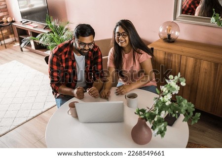 Latino or indian man and woman couple use their laptop in the living room to make video calls. Video call and online chat with family