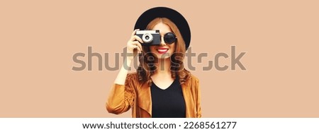 Portrait of happy smiling young woman photographer with film camera on brown background