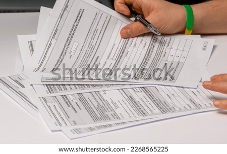 Completing and submitting a tax form.  Annual return held by the taxpayer in his hands.  Documents on the desk.  pit37, pit28 Royalty-Free Stock Photo #2268565225