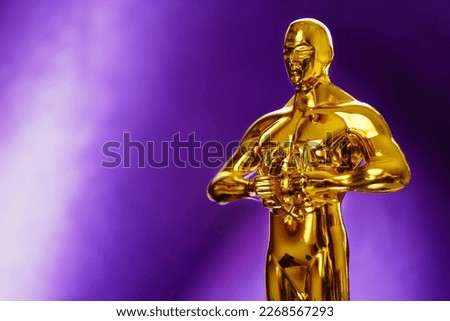 Hollywood Golden Oscar Academy award statue on violet background. Success and victory concept.