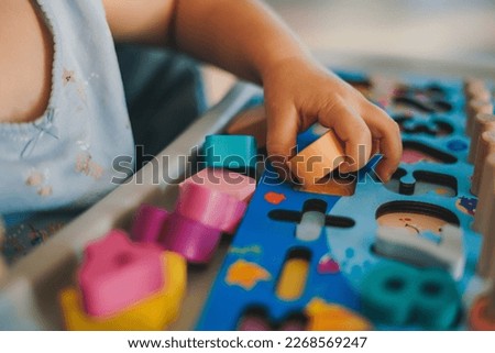 Close-up view of baby's hands playing in a puzzle made of colorful figurines. Education concept. Family activity concept. Happy family kid concept. Lifestyle