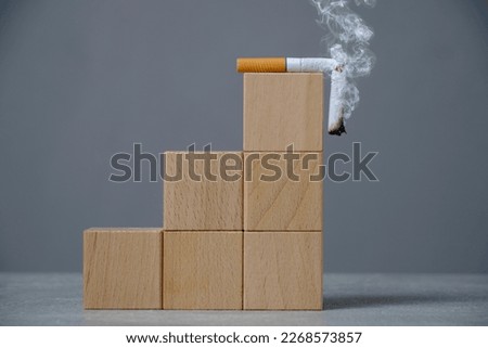 Top wooden ladder of cubes lies a broken, smoking cigarette.Concept World No Tobacco Day