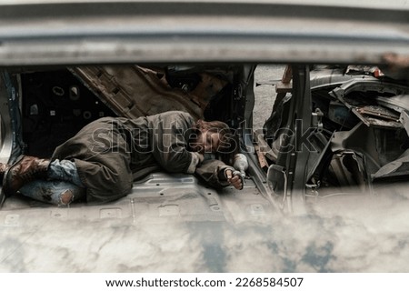 a homeless man sleeps in a car dump