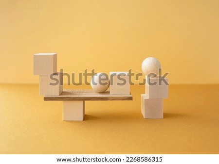 Balanced horizontal geometric composition of different wooden figures on yellow background.