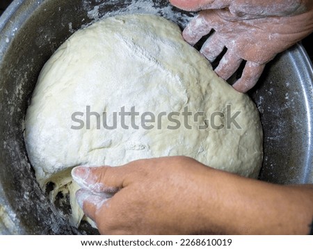 Raw thick dough in the hands of a woman baker. Ready dough for baking in a pan. Test batch. Cook's hands. Opara. Bread preparation. Kneaded yeast dough. Unprepared. calorie product. Bakery Royalty-Free Stock Photo #2268610019