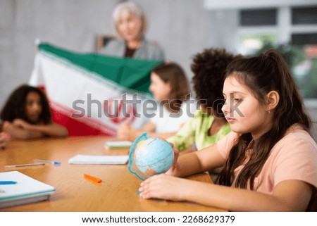 at lesson, attentive children listen to teacher s story about physical geography of Iran