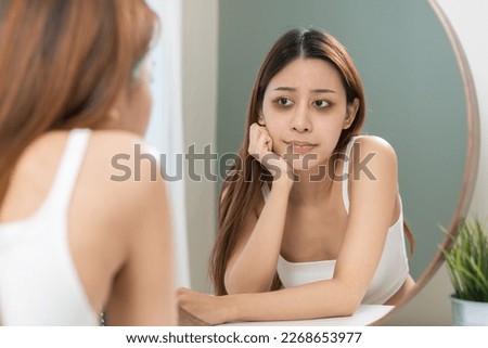 Bored, insomnia asian young woman, girl looking at mirror hand touching under eyes with problem of black circles or panda puffy, swollen and wrinkled on face. Sleepless, sleepy healthcare person.