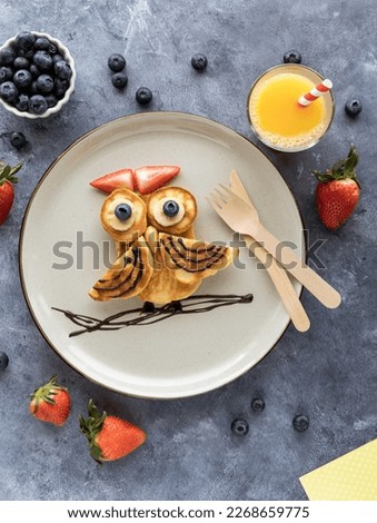 pancakes in the shape of an owl, served with fruit and juice.
