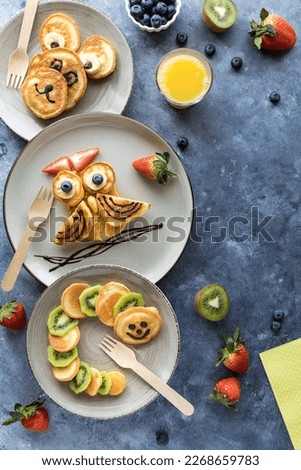 Pancakes in the shapes of critters, served with fruit and juice for kids.