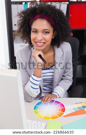 Portrait of smiling female photo editor sitting at office desk