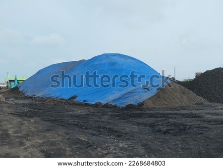pile of coal covered with tarpaulin to anticipate getting wet from the rain Royalty-Free Stock Photo #2268684803