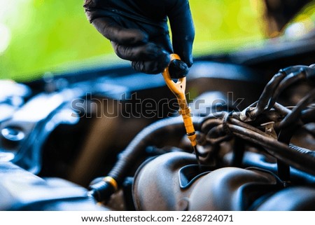 oil dipstick, lubrication In the hands of black rubber gloves,  Do-it-yourself car inspection, selective focus, soft focus.     Royalty-Free Stock Photo #2268724071
