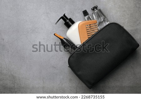 Preparation for spa. Compact toiletry bag with different cosmetic products on grey textured background, flat lay. Space for text Royalty-Free Stock Photo #2268735155