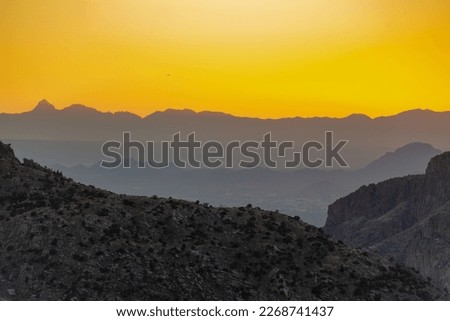 Orange yellow sunset light with rolling mountain and cliff hills in tuscon arizona late in the day with hazy ridgeside valleys. In sonora desert in wild west north america the great outdoors.