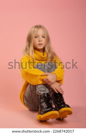 Beautiful school girl sitting on the floor, colorful studio background