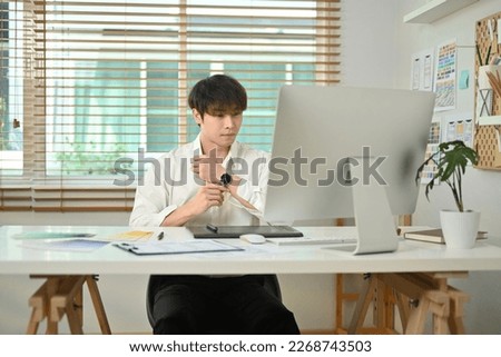 Handsome asian male website developer working on mobile application software design project at his workstation