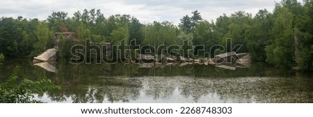 Panorama photo of a river with a forest with large stones on and next to each other