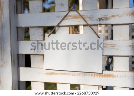 rustic wooden white lattice work with a white hanging picture sign with empty free space for template or blank copy area