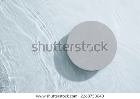 A gray circle podium isolated on the water surface background. Product promotion. Beauty cosmetic showcase.