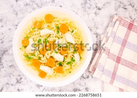 Homemade chicken soup with noodles and vegetables in a white bowl,on a gray  background. Healthy warm comfortable food.