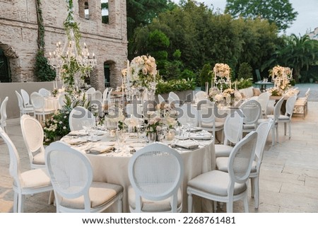 White color wedding table decorated with decorative and elegant for wedding. There are flowers, candles and serving plates on the wedding table. Royalty-Free Stock Photo #2268761481