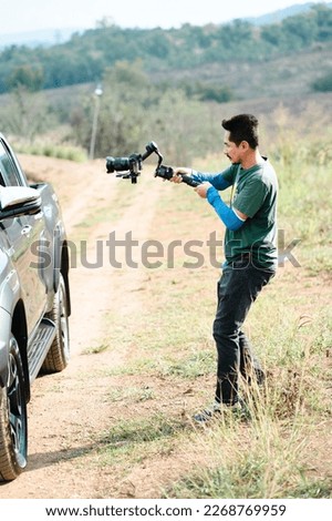 Young Professional videographer holding professional camera on 3-axis gimbal stabilizer. Pro equipment helps to make high quality video without shaking. Cameraman Asian making a videos.