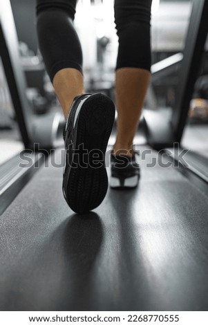 Close up of sole of sneakers of unrecognizable athlete jogging on a treadmill. Royalty-Free Stock Photo #2268770555