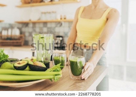 Matcha green vegan smoothie with chia seeds and mint in glass in hands of female wearing white sweater, square crop. Clean eating, alkaline diet, weight loss food concept. Royalty-Free Stock Photo #2268778201