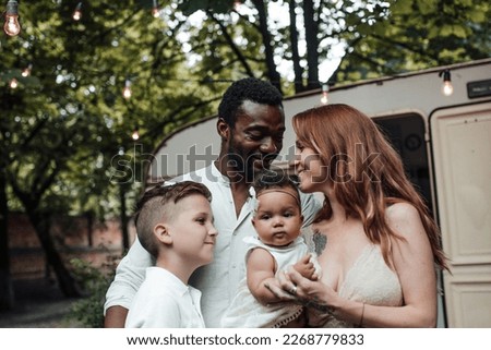 Mixed race family with white son and infant swarthy daughter spend time together in camper park outdoor. African american man with his fair skinned wife and kids enjoying summer vacation in open air Royalty-Free Stock Photo #2268779833