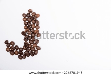 J is a capital letter of the English alphabet made up of natural roasted coffee beans that lie on a white background. Plenty of space to put text or pictures, top view and studio photography.