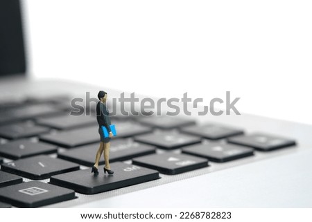 Miniature people toy figure photography. A businesswoman standing above notebook laptop keyboard. Isolated on white background. Image photo