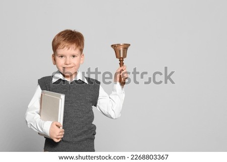 Pupil with school bell and books on light grey background. Space for text
